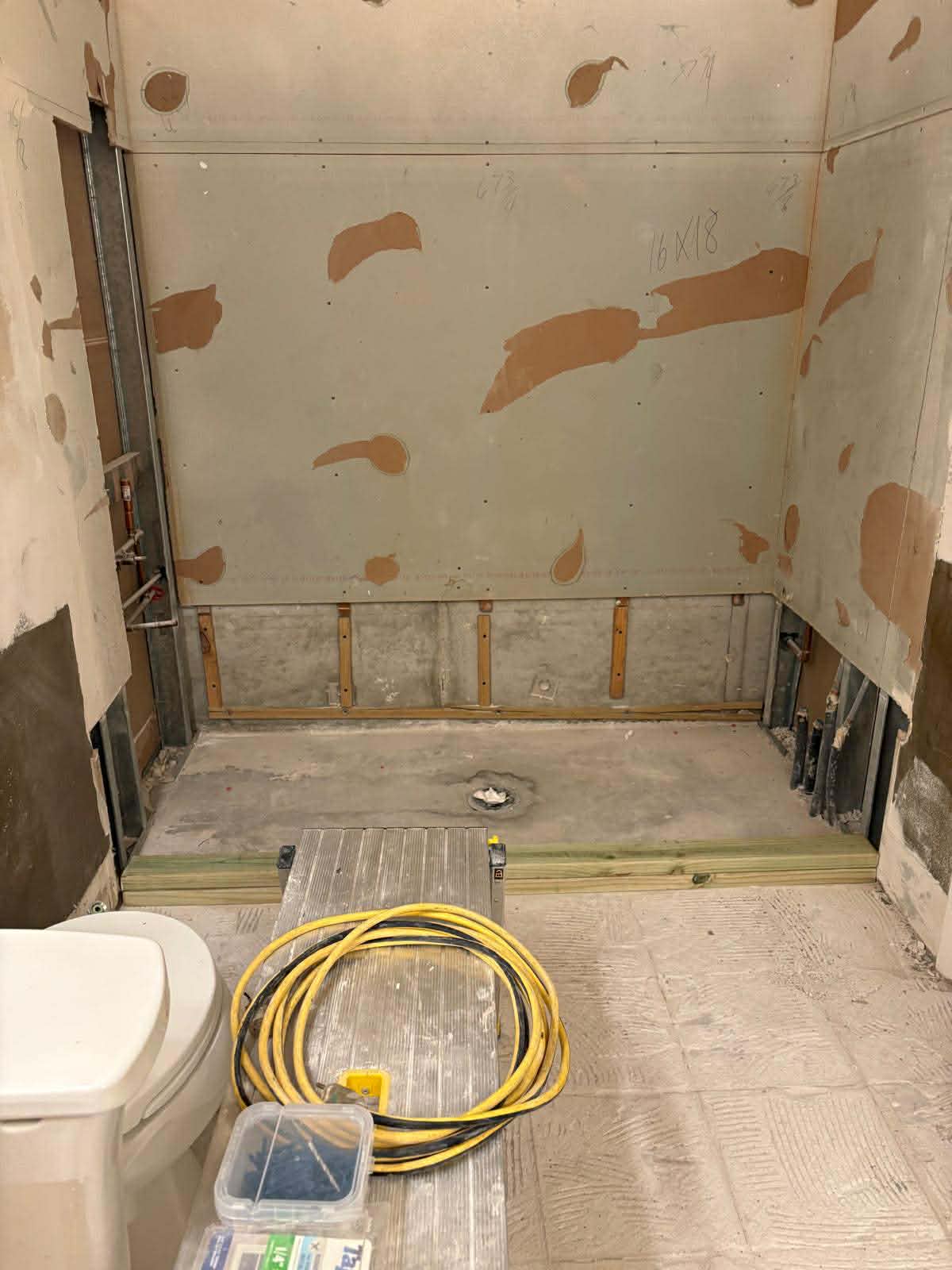 Bathroom demolition phase with old fixtures removed and walls stripped by Custom Bath and Tile crew