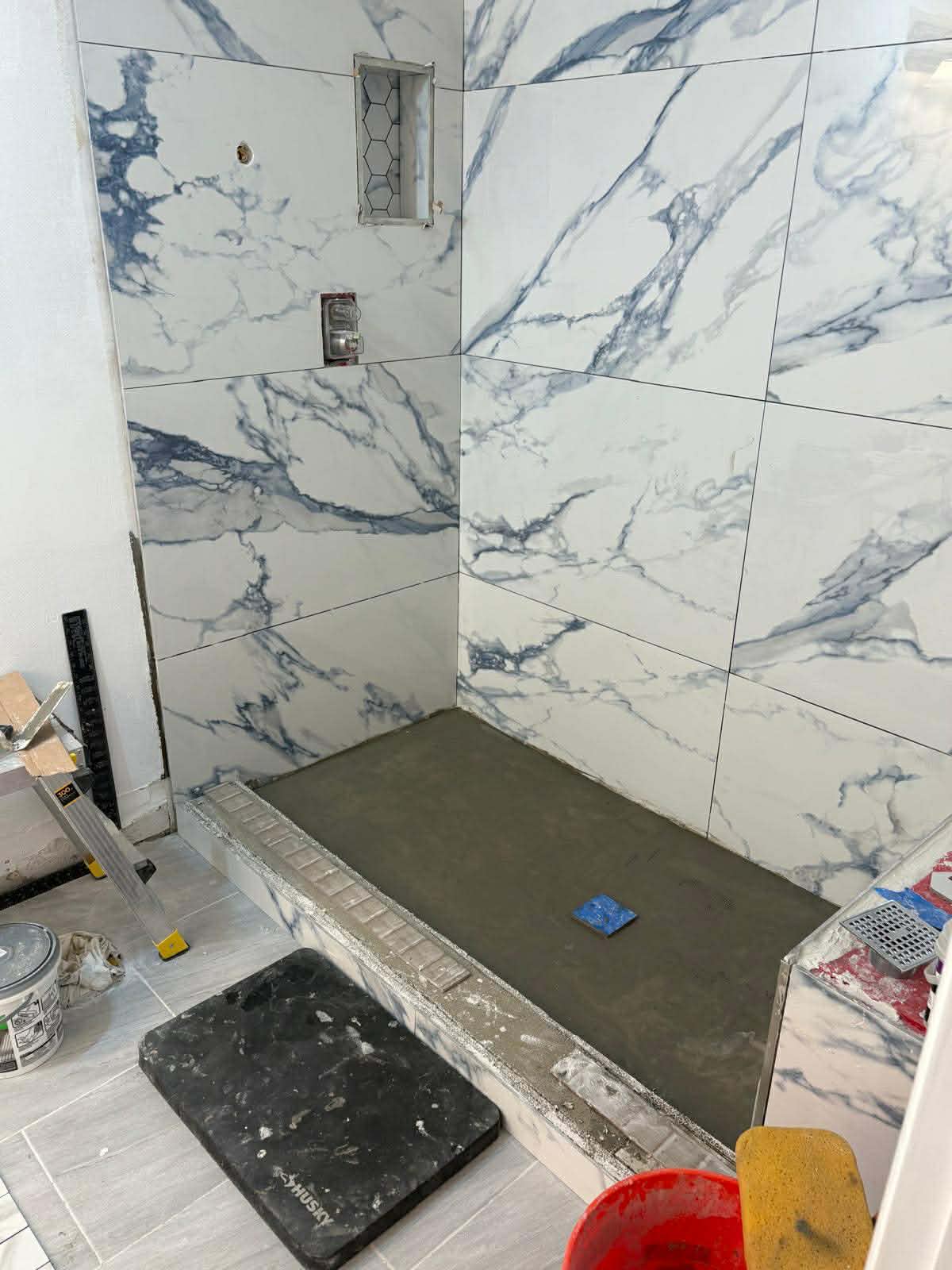 Professional marble tile installation in progress on shower walls by Custom Bath and Tile craftsmen